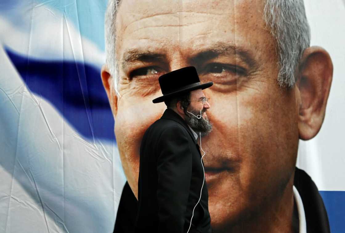 An Ultra Orthodox Jewish man walks past an electoral billboard bearing a portrait of Israel's then prime minister Benjamin Netanyahu back in 2019 -- one of the many national polls Israelis have voted in during recent years