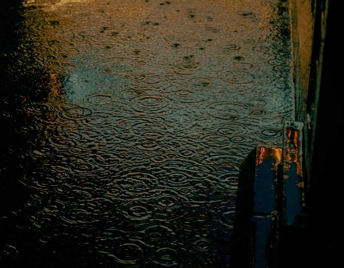 Rainwater ripples across a flooded street at night. Rainwater ripples across a flooded street at night.
