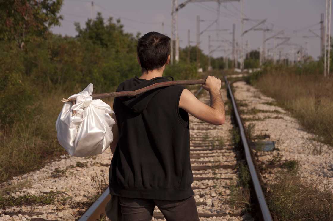 A white man is holdig a stick over his shoulder A white man is holdig a stick over his shoulder