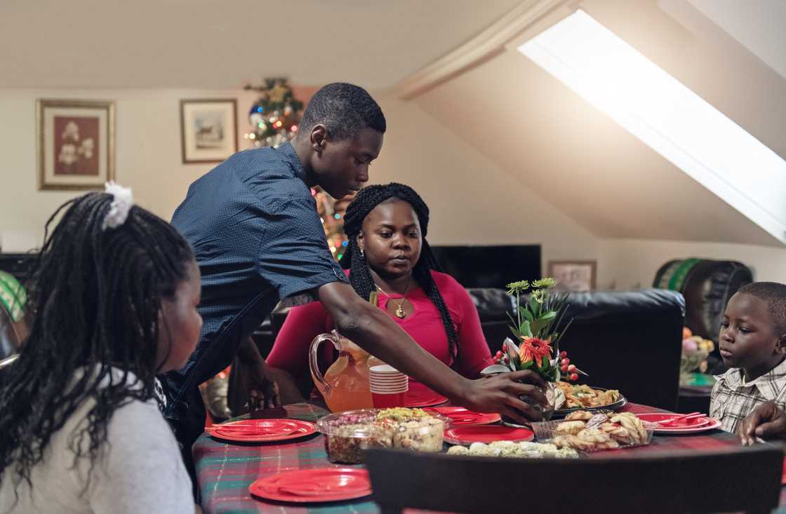 Family gathers around a holiday table with festive dishes.