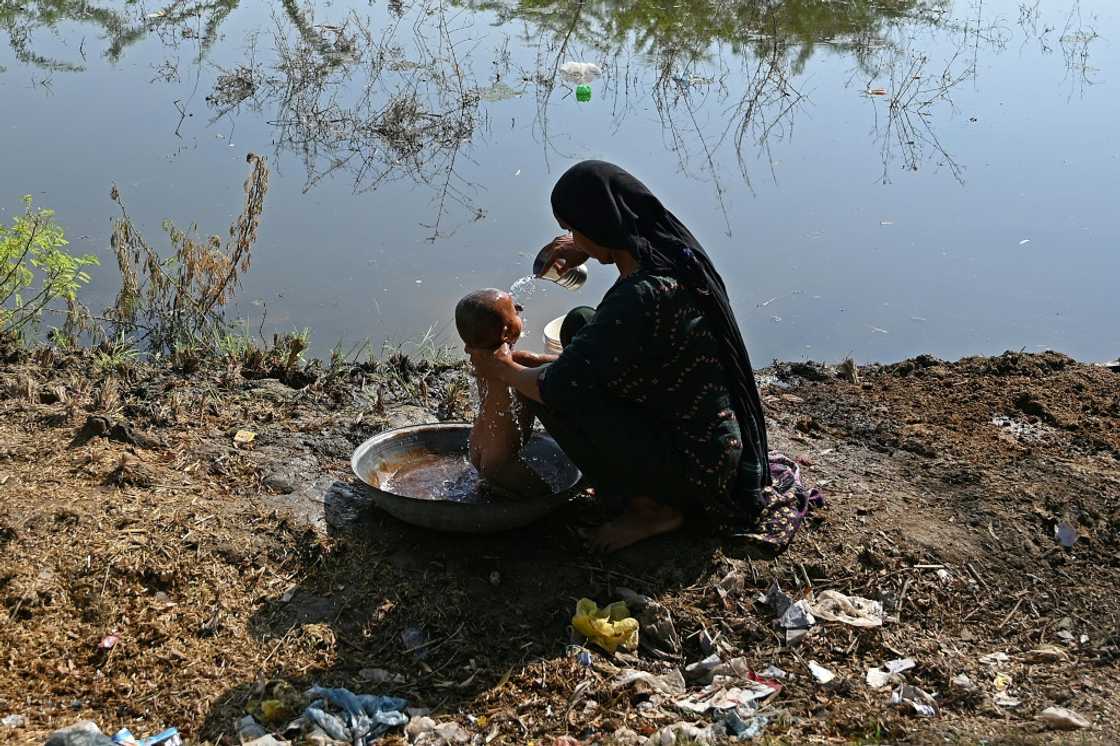 A woman bathes her child next to a flooded field in southern Pakistan A woman bathes her child next to a flooded field in southern Pakistan