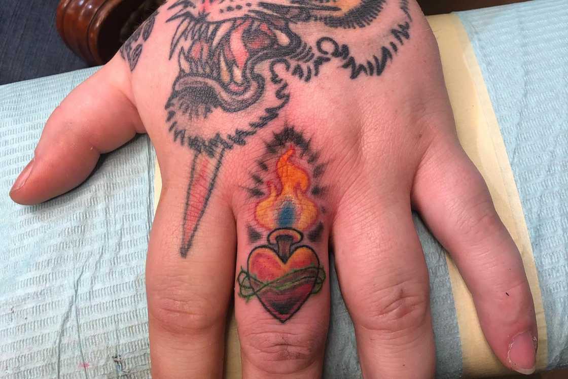 A sacred heart tattoo on the middle finger