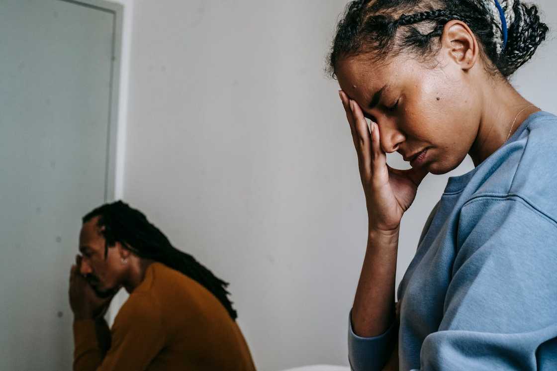 A mother crying softly as her adult son stands nearby.