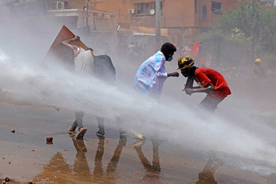 Sudan has seen months of anti-coup protests; here demonstrators take cover as riot police try to disperse them with a water cannon during a demonstration against military rule on June 30 Sudan has seen months of anti-coup protests; here demonstrators take cover as riot police try to disperse them with a water cannon during a demonstration against military rule on June 30