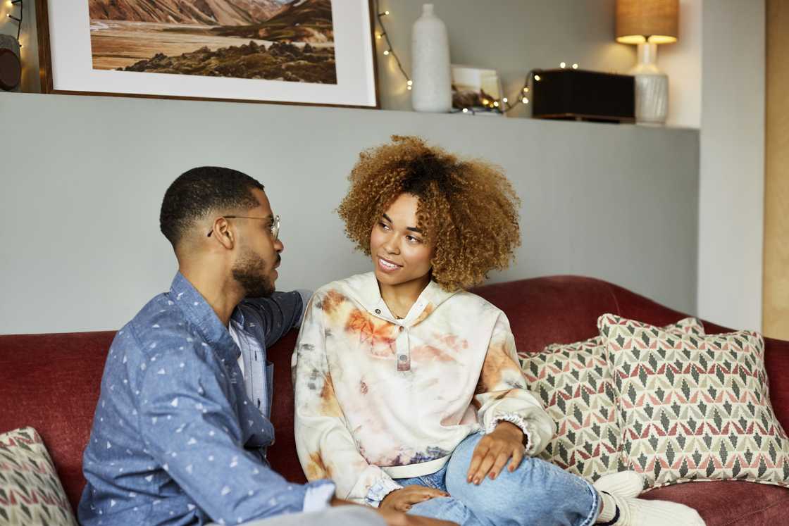 A young couple discuss in a living room apartment.