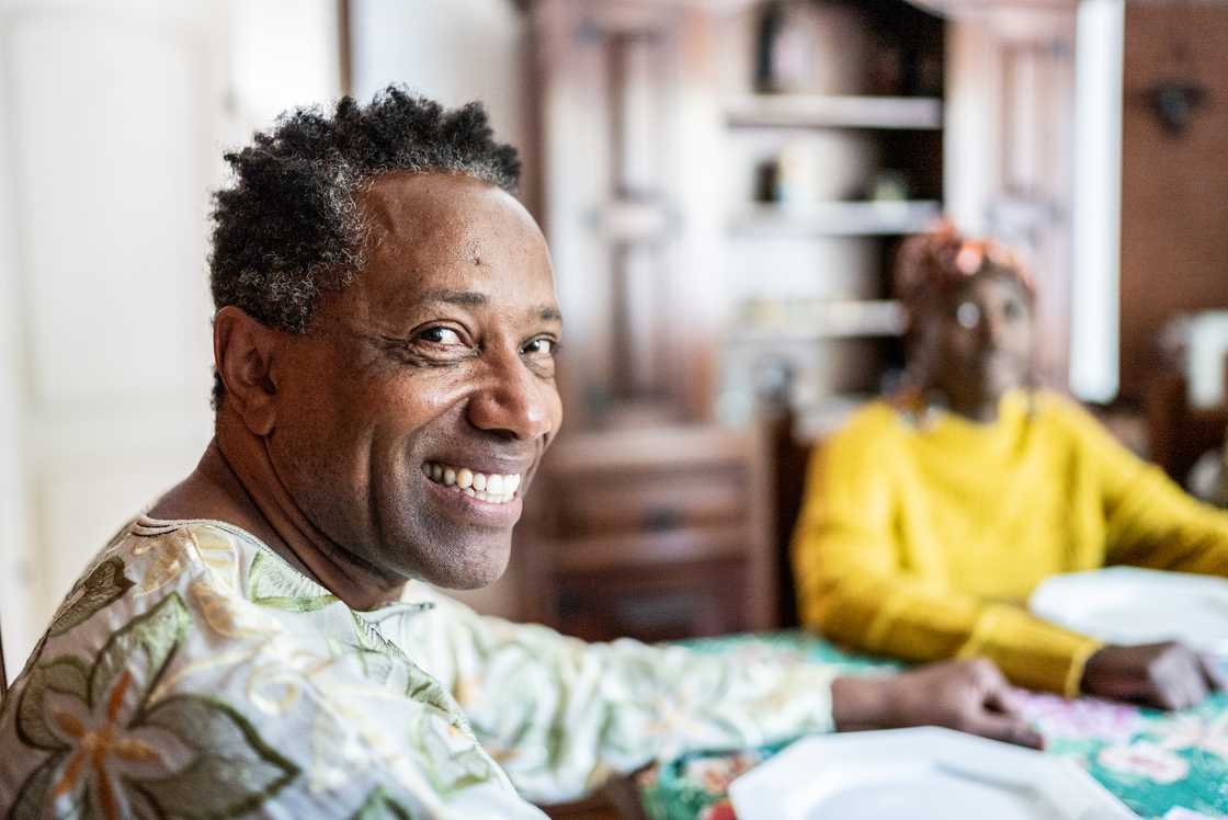 Two people sit at a table in a home setting. Two people sit at a table in a home setting.