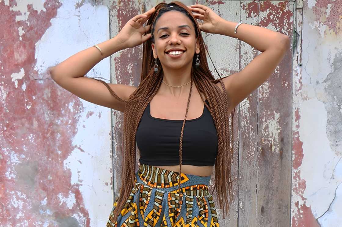 A happy woman wears a black top with a long African printed skirt