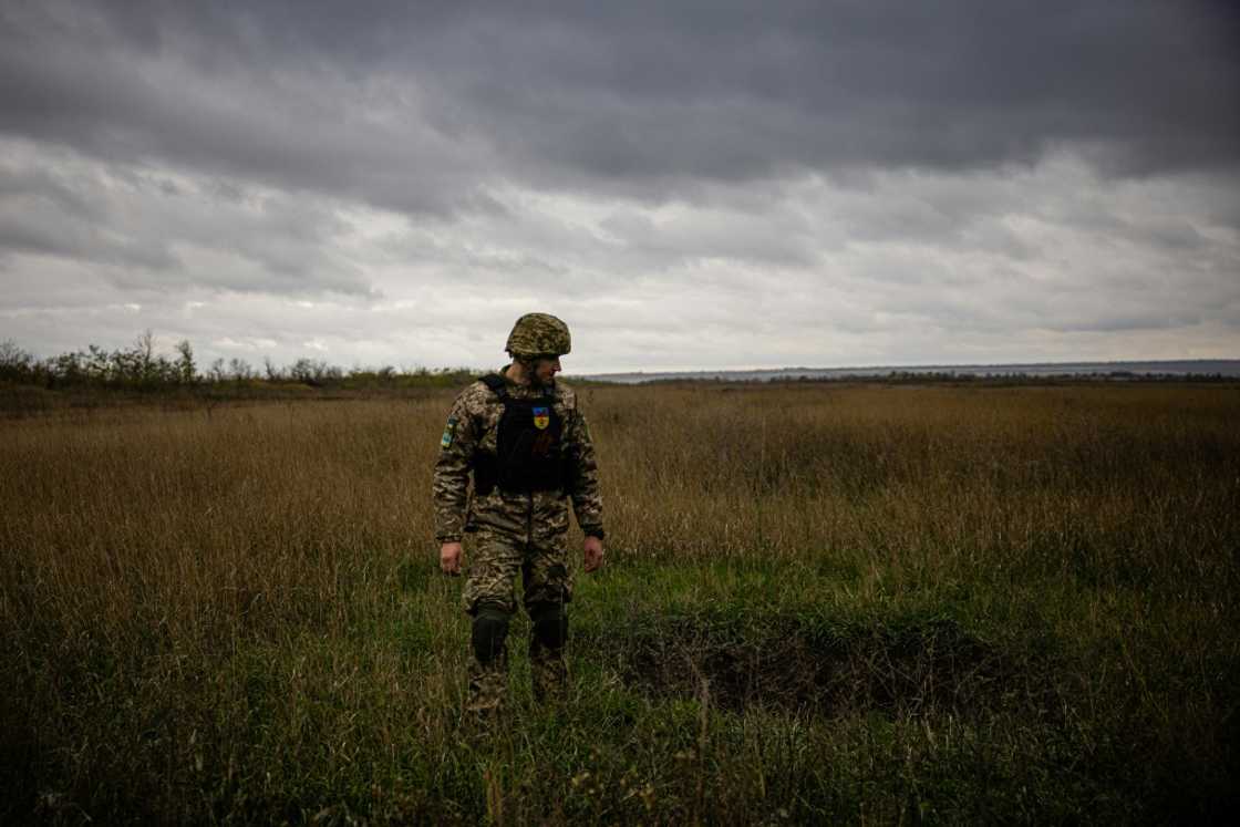 A Ukrainian serviceman stands next to a mortar crater in a field in the Donetsk region of eastern Ukraine A Ukrainian serviceman stands next to a mortar crater in a field in the Donetsk region of eastern Ukraine