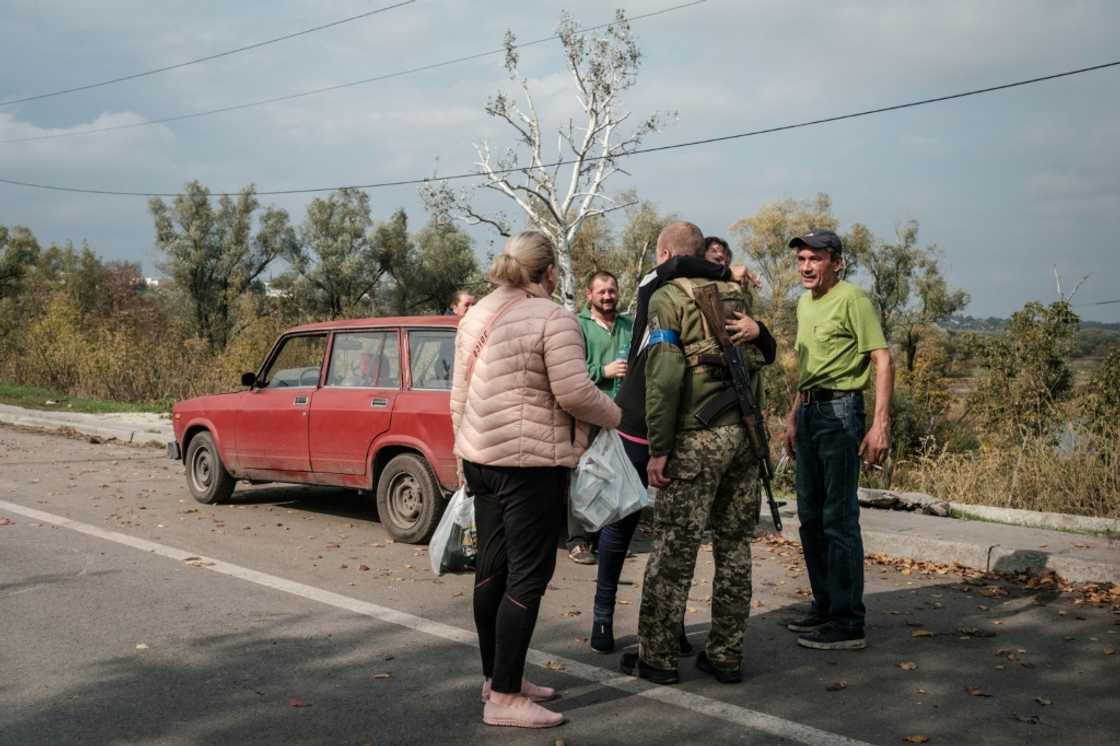 Locals embrace a Ukrainian soldier on a road in Kupiansk