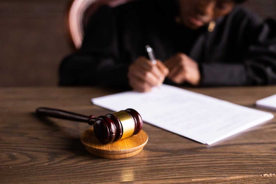 Judge's gavel on a desk with a person signing legal documents. Judge's gavel on a desk with a person signing legal documents.