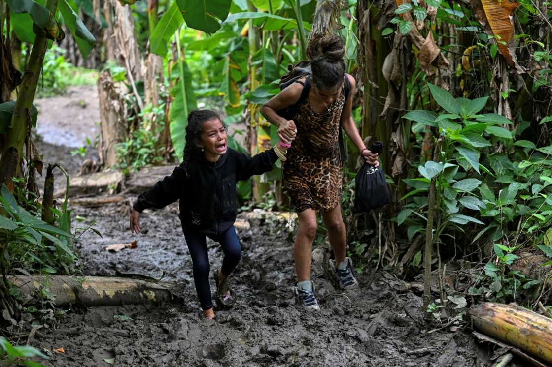 A Venezuelan migrant girl is helped by her mother as they arrive at Canaan Membrillo village in the Darien Jungle A Venezuelan migrant girl is helped by her mother as they arrive at Canaan Membrillo village in the Darien Jungle