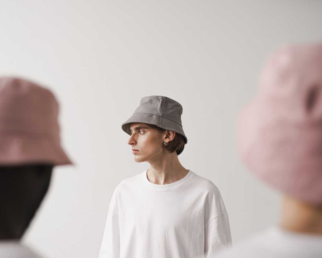 A young man in a white T-shirt and grey bucket hat looking sideways A young man in a white T-shirt and grey bucket hat looking sideways