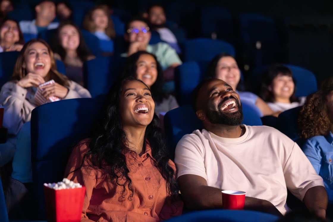 Happy couple laughing while watching a movie at the theatre