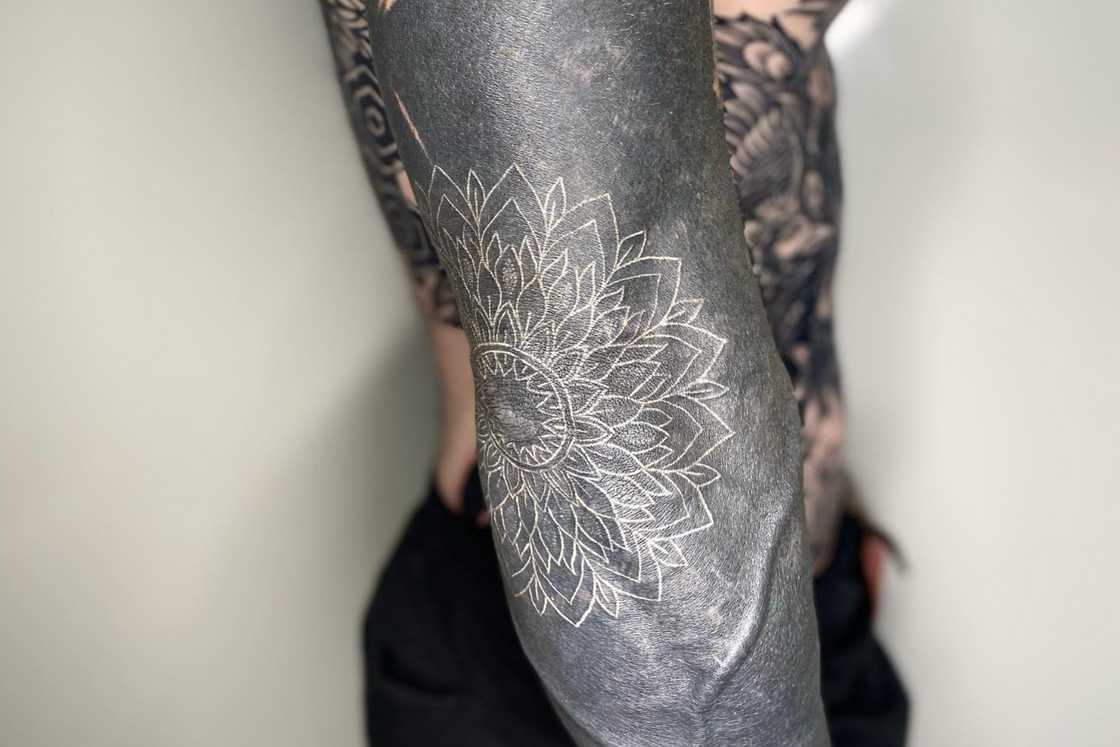 A photo of white on black elbow tattoo A photo of white on black elbow tattoo