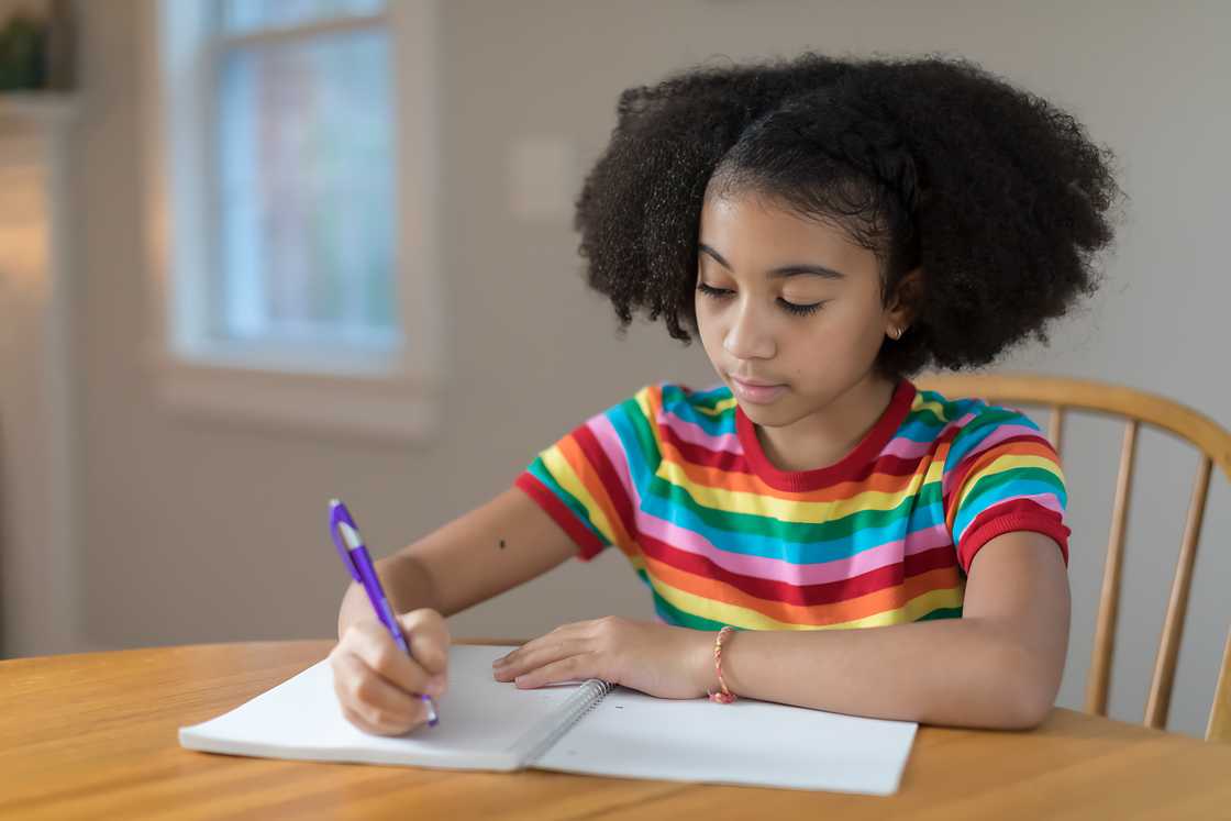 A ten-year-old bi-racial girl is writing