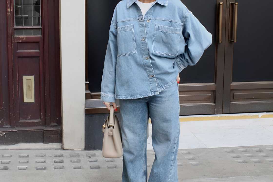 A lady holding a handbag is wearing a double denim outfit A lady holding a handbag is wearing a double denim outfit