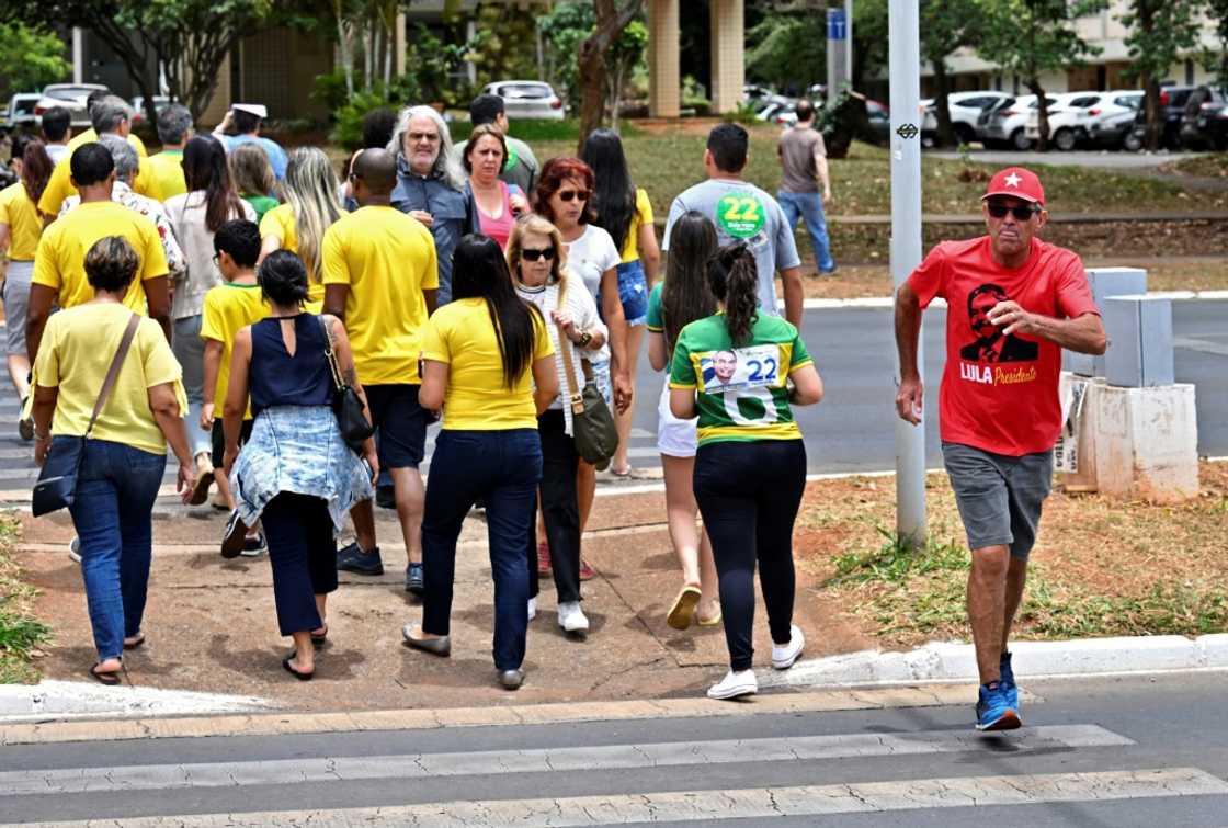 A supporter (R) of former president Luiz Inacio Lula da Silva walks in the other direction to supporters of president and election rival Jair Bolsonaro, as they cross a street in Brasilia, on October 30, 2022, during the presidential run-off A supporter (R) of former president Luiz Inacio Lula da Silva walks in the other direction to supporters of president and election rival Jair Bolsonaro, as they cross a street in Brasilia, on October 30, 2022, during the presidential run-off