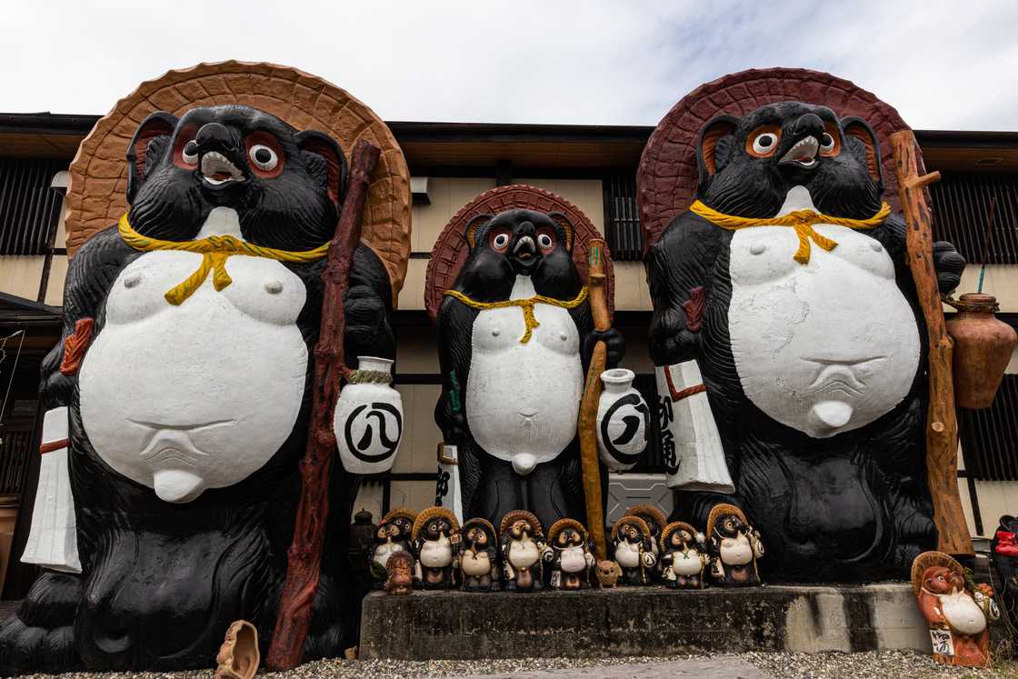 Tanuki figurines and large clay pots are dotted along the side of the road