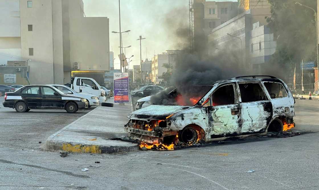 Damaged vehicles are pictured on a street in the Libyan capital Tripoli on August 27, 2022, following clashes between rival Libyan groups