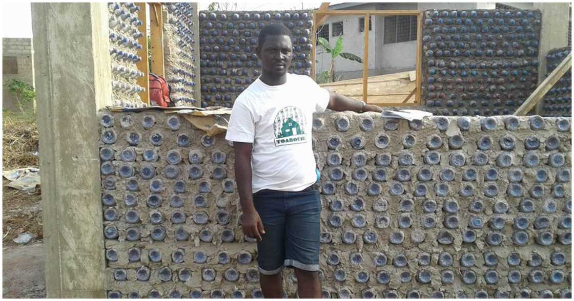 Man stands by a house he is building with plastic bottles Man stands by a house he is building with plastic bottles