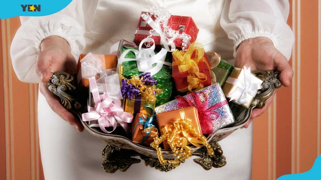 A woman holds a bowl full of little gift boxes. A woman holds a bowl full of little gift boxes.