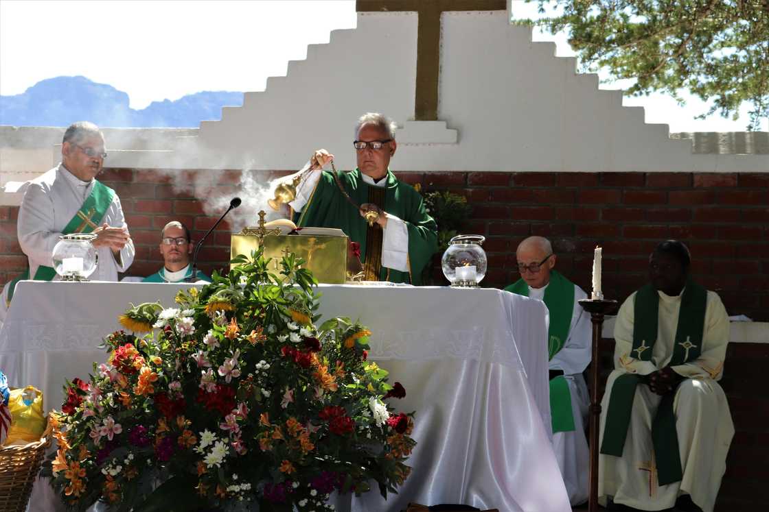 Senior priest waving incense during church service near multiracial coworkers Senior priest waving incense during church service near multiracial coworkers