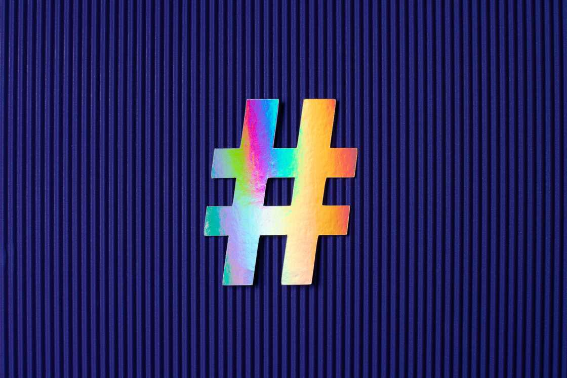 Holographic coloured hashtag paper craft on purple corrugated paper background Holographic coloured hashtag paper craft on purple corrugated paper background