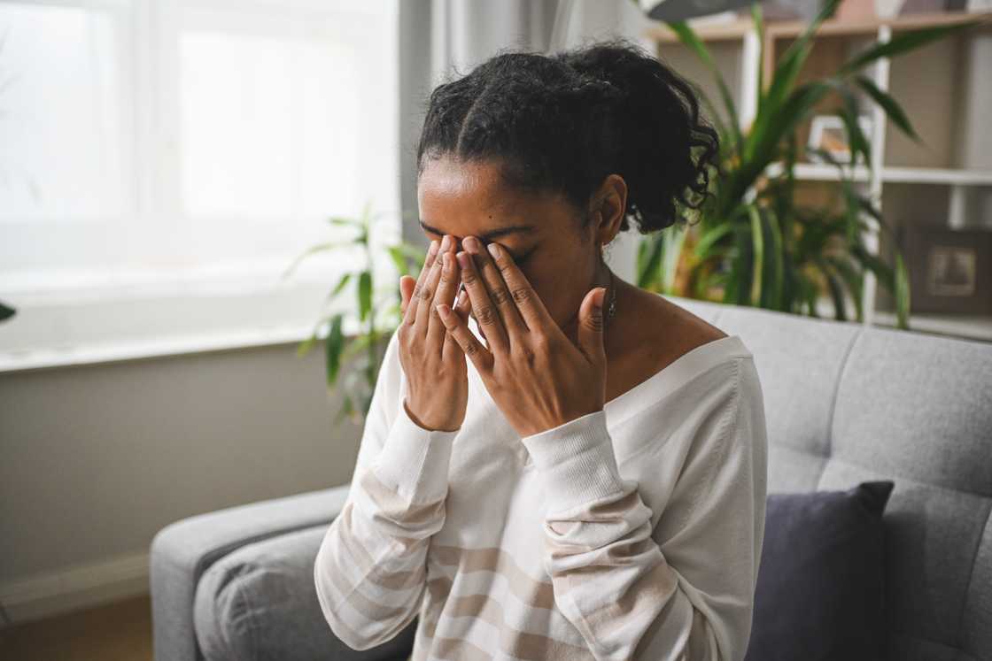 A distraught black woman is sitting on a sofa A distraught black woman is sitting on a sofa