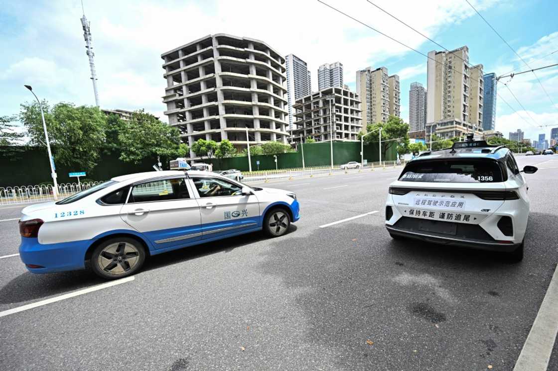 A regular taxi passes a driverless one in Wuhan, home to one of the world's largest robotaxi networks