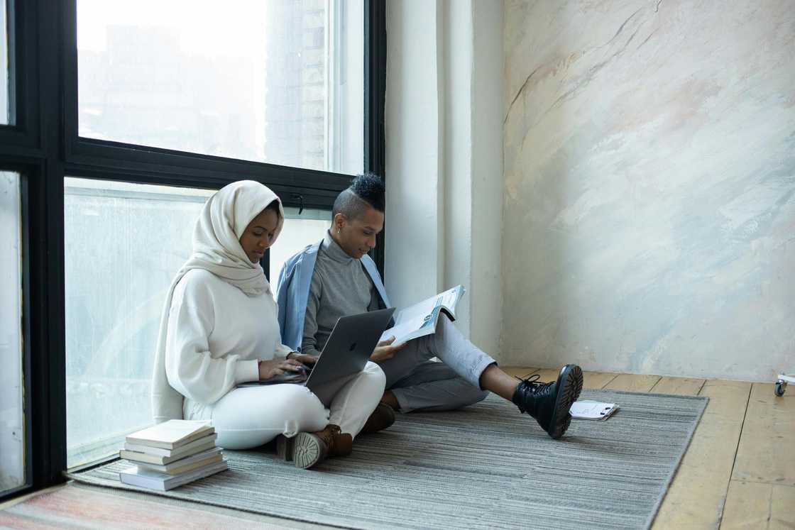 A male and female student doing an assignment on the floor A male and female student doing an assignment on the floor