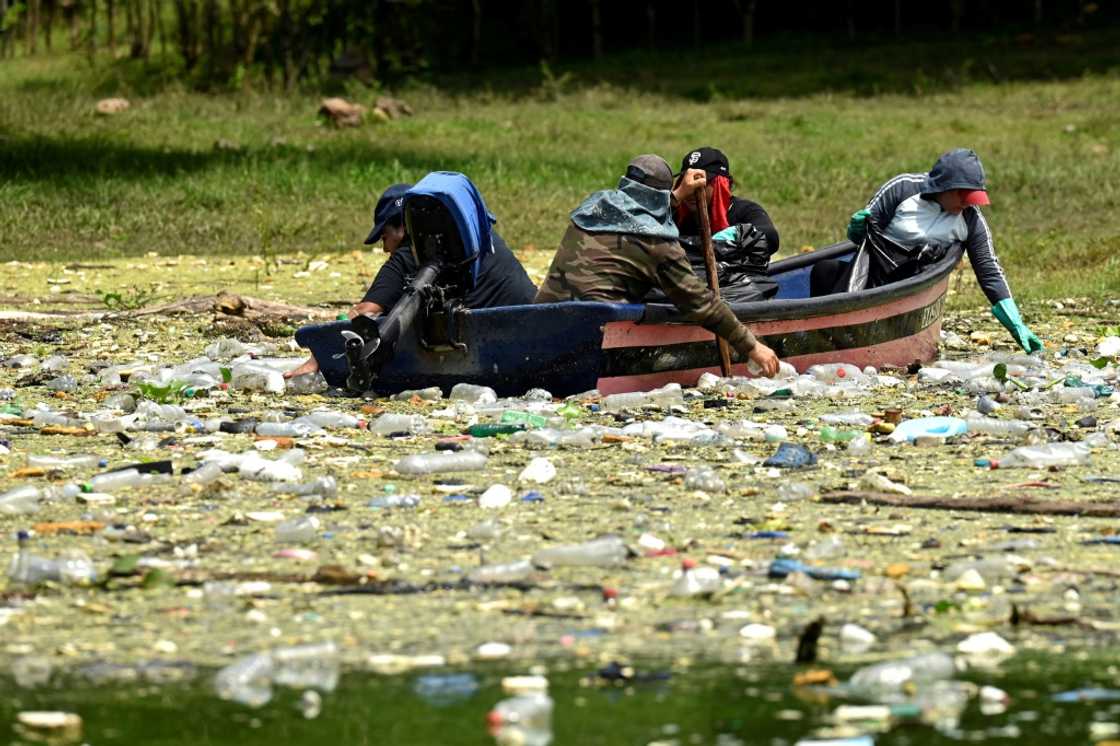 People in a boat clean up plastic rubbish from the Cerron Grande in Potonico, El Salvador by hand People in a boat clean up plastic rubbish from the Cerron Grande in Potonico, El Salvador by hand