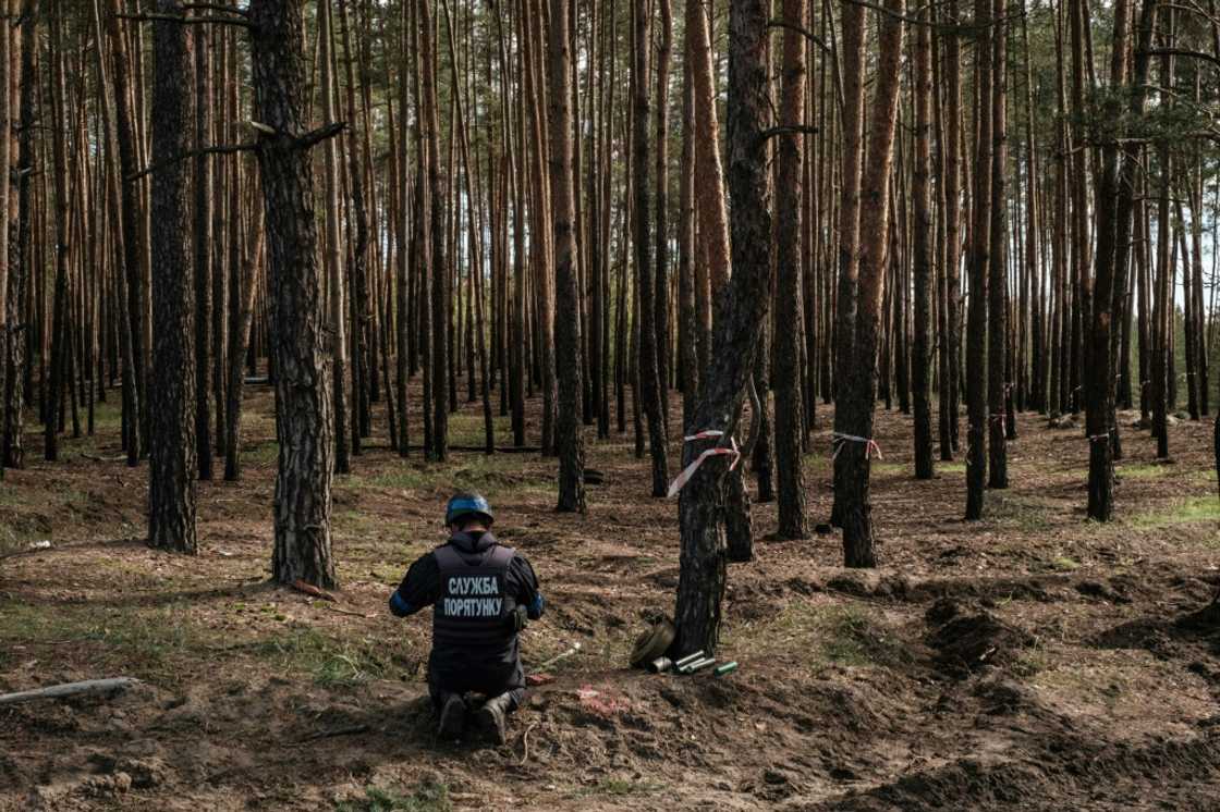 A Ukrainian national police emergency demining team's officer prepares to detonate collected anti-tank mines and explosives near the recently retaken town of Lyman in Donetsk region