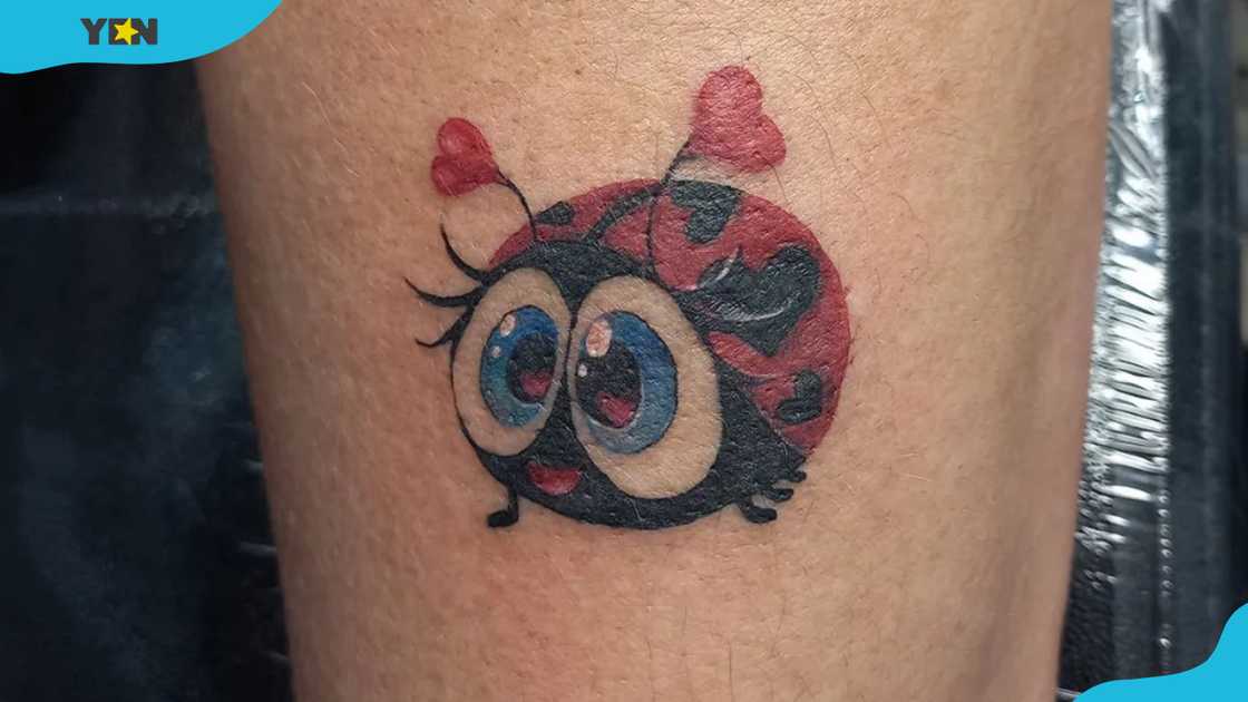 A cute cartoon-style ladybug tattoo with large blue eyes