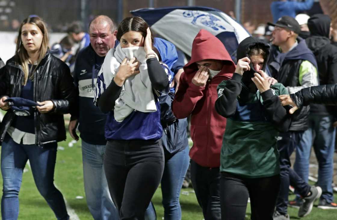 Fans of Gimnasia y Esgrima escape unrest nad tear gast by reaching the soccer pitch after violence and police operations near an Argentina soccer match between Gimnasia and Boca Juniors in La Plata