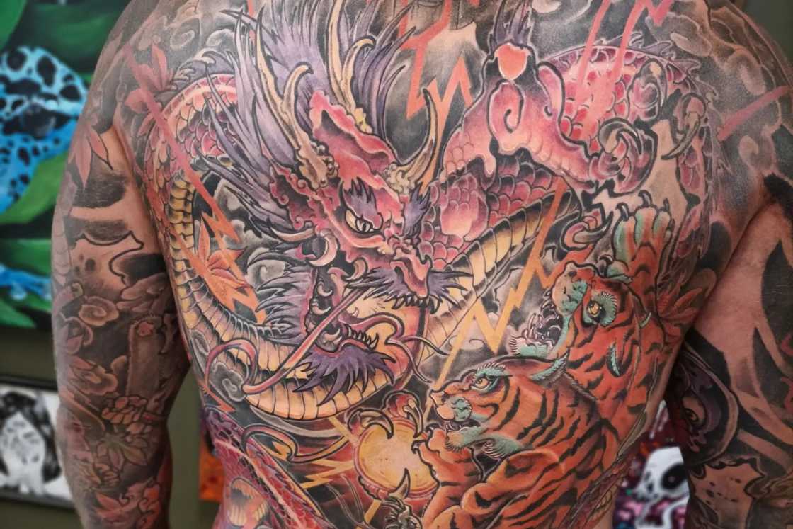 A man has an intricate dragon tattoo on his back A man has an intricate dragon tattoo on his back