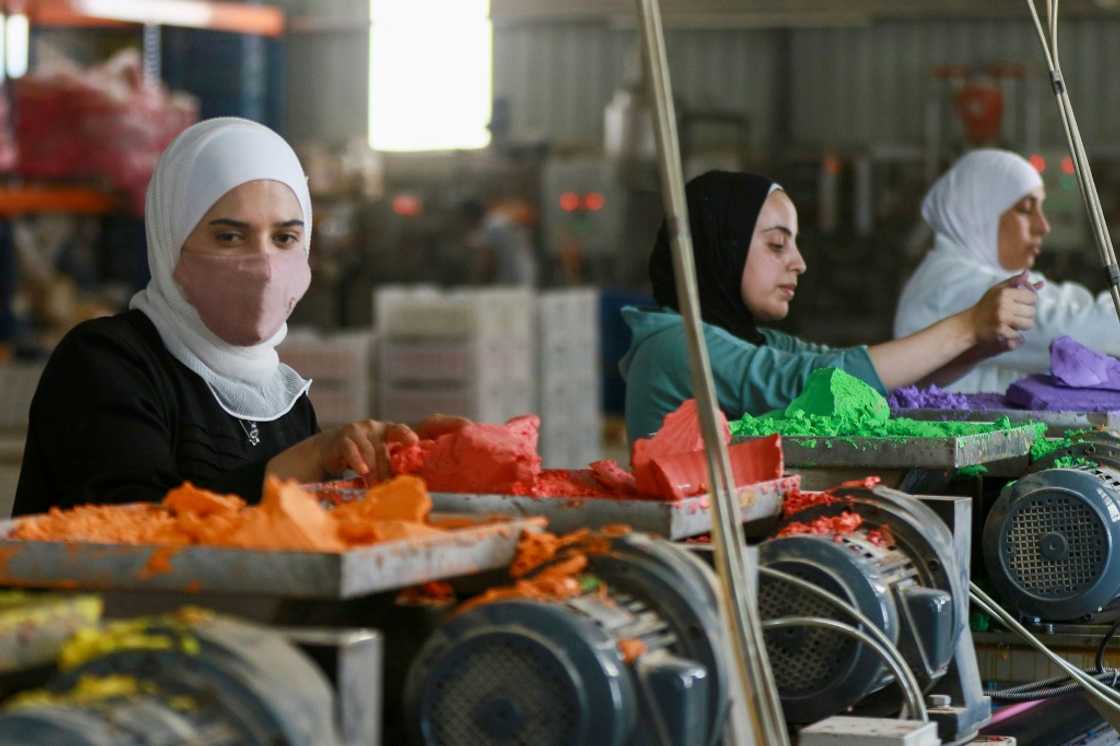 Jordanian workers put coloured chalk through a machine in the factory in Karak, south of the capital Amman