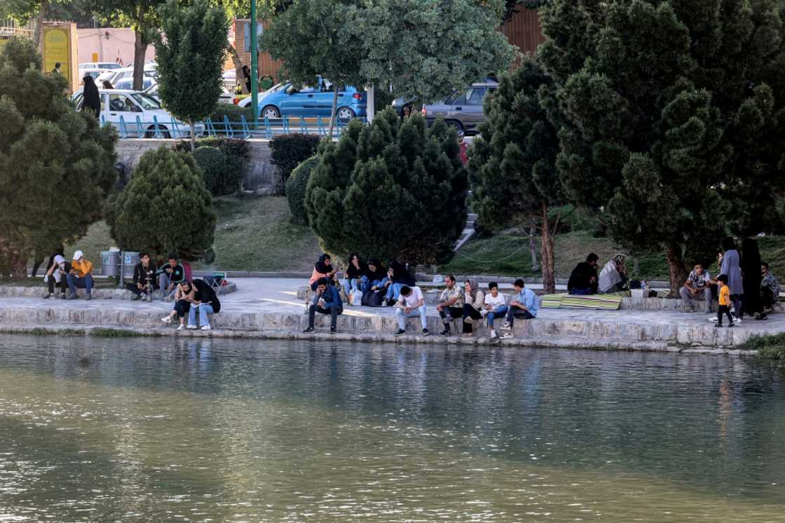 A file picture shows people sitting along the bank of the Zayandeh Rood river on May 15, 2022 in Iran's central city of Isfahan -- the river has been drying out, but families seek out riversides and other cooler areas to relax during the summer A file picture shows people sitting along the bank of the Zayandeh Rood river on May 15, 2022 in Iran's central city of Isfahan -- the river has been drying out, but families seek out riversides and other cooler areas to relax during the summer