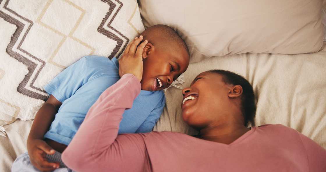 A mom laughing in bedroom with her son