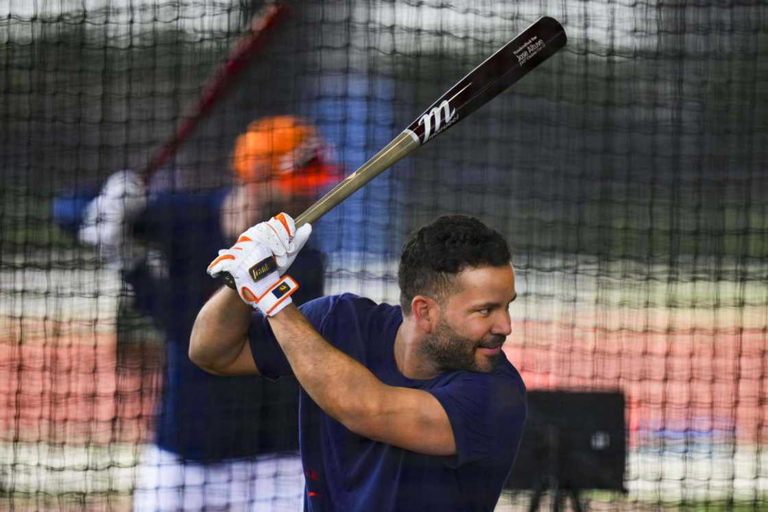 A man in a batting cage gripping a baseball bat, ready to swing. A man in a batting cage gripping a baseball bat, ready to swing.