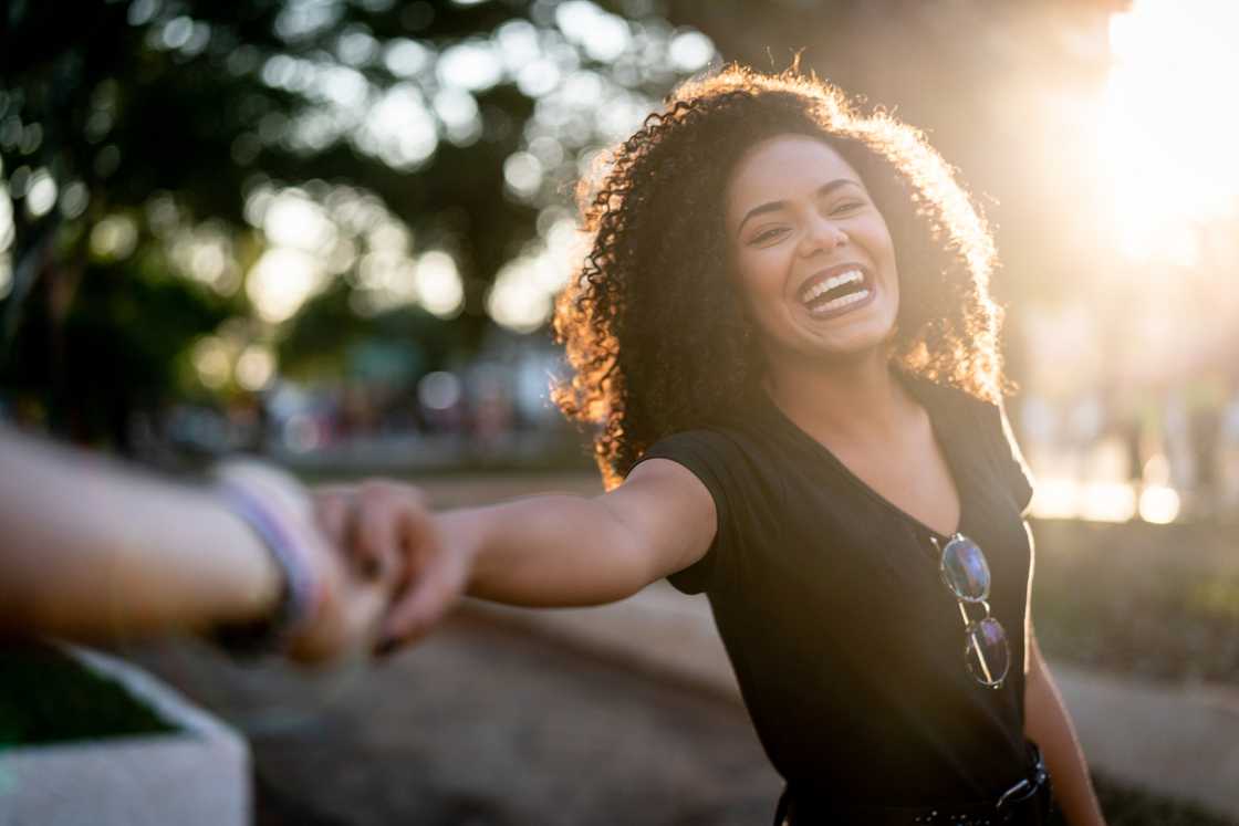 A happy woman with a curly hair holding her boyfriend's hand A happy woman with a curly hair holding her boyfriend's hand