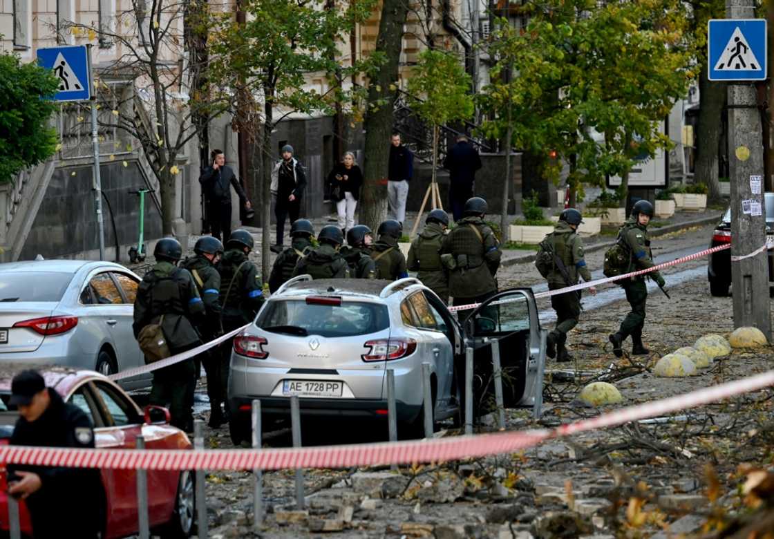 Ukrainian servicemen walk past damaged cars in the centre of Kyiv after several Russian strikes hit the Ukrainian capital