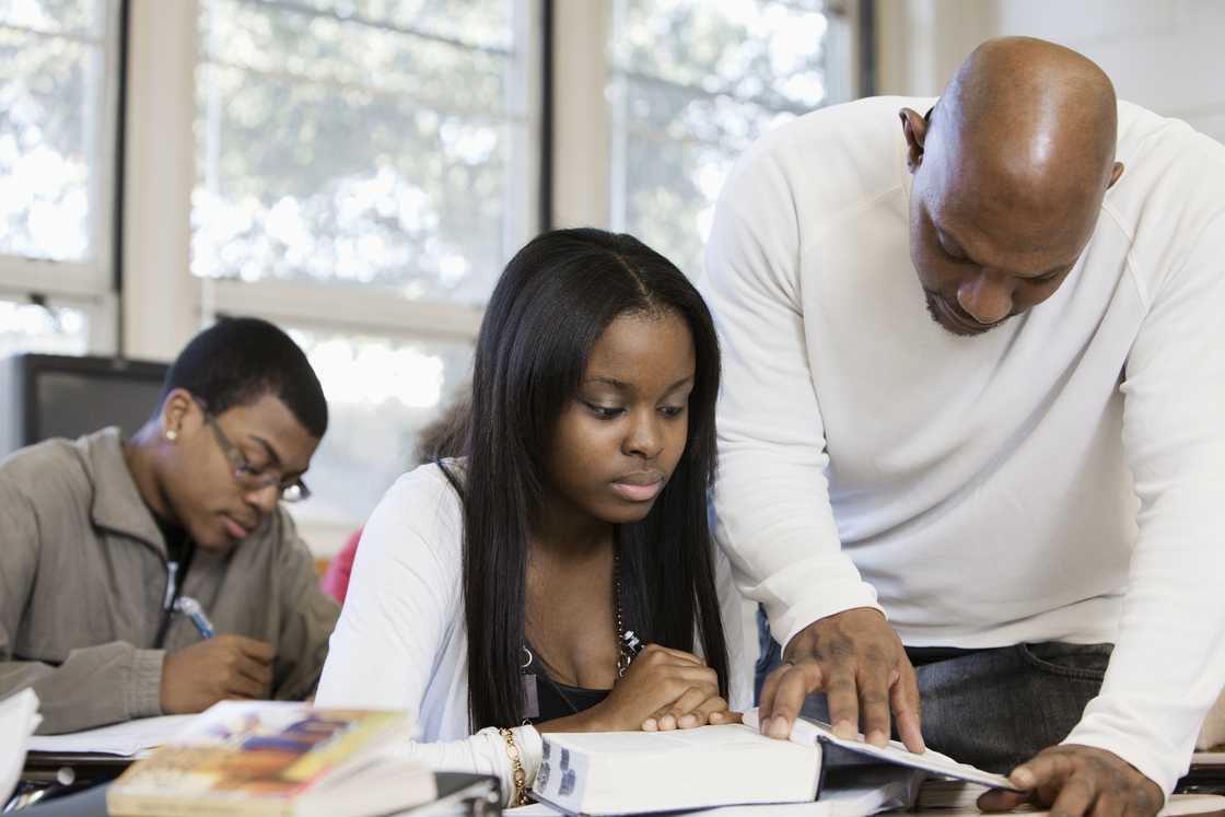 Teacher helping a student in a classroom. Teacher helping a student in a classroom.