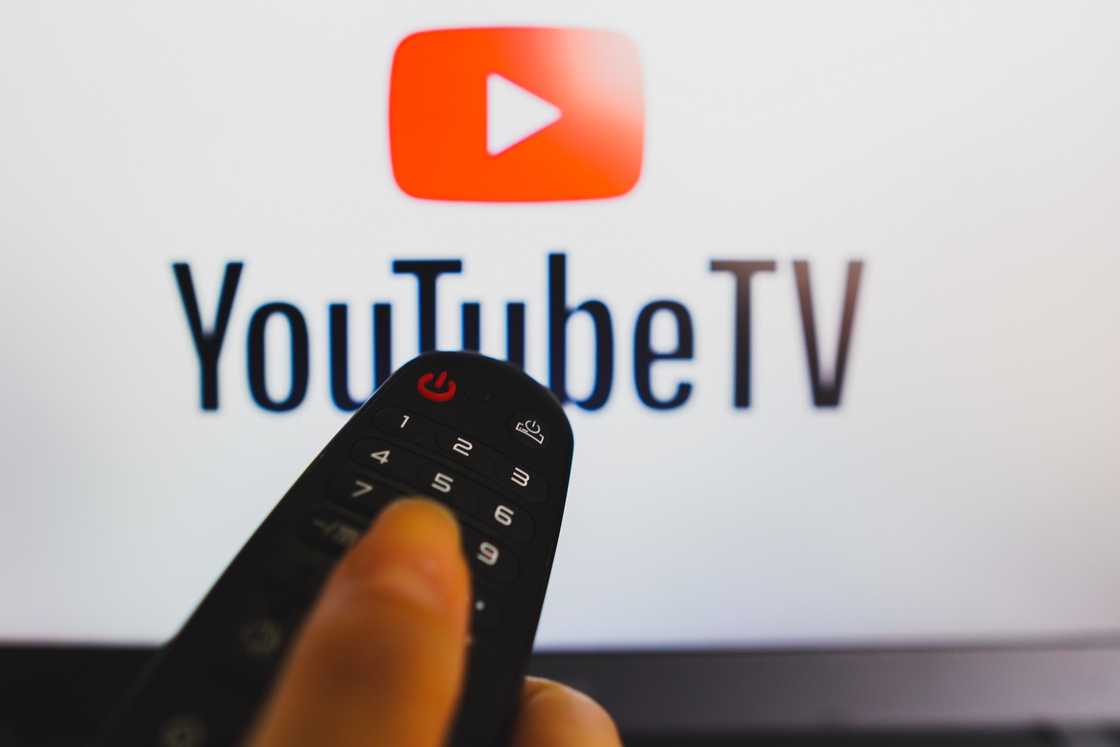 YouTube TV logon on a screen and a person's hand holding a remote control. YouTube TV logon on a screen and a person's hand holding a remote control.