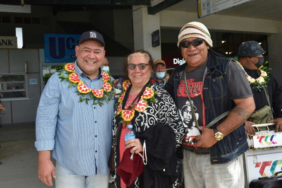 Etu Palu, left, and his mother Finau Palu, centre, are greeted upon arriving on the first flight into Tonga under the new open border policy at Fua'amotu International Airport