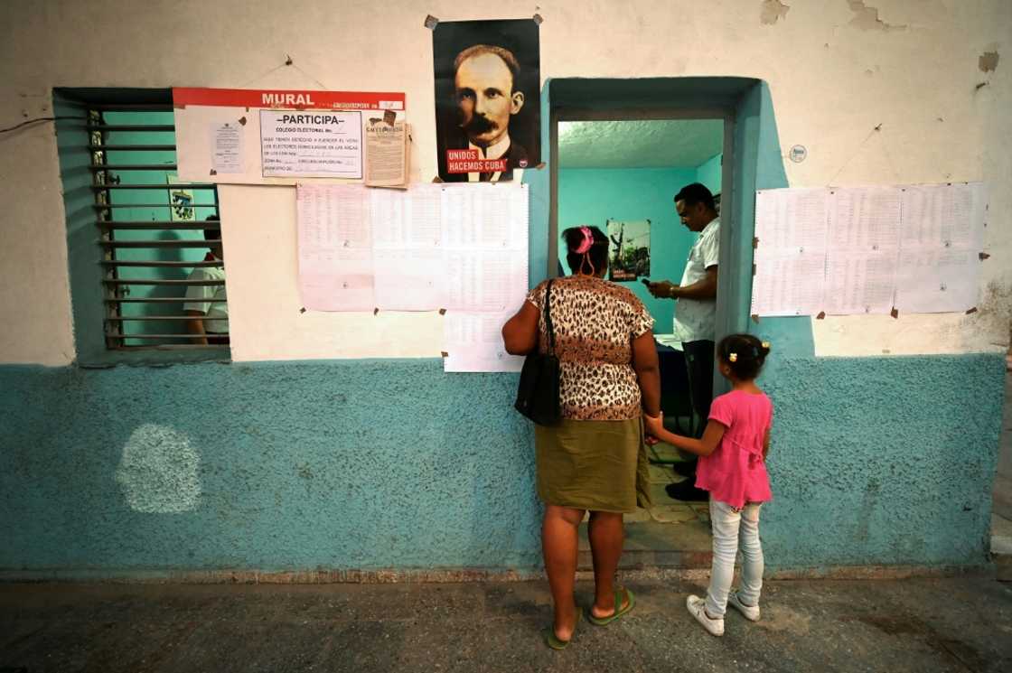 A woman, accompanied by her daughter, waits to vote on the new Family Code at a Havana polling station