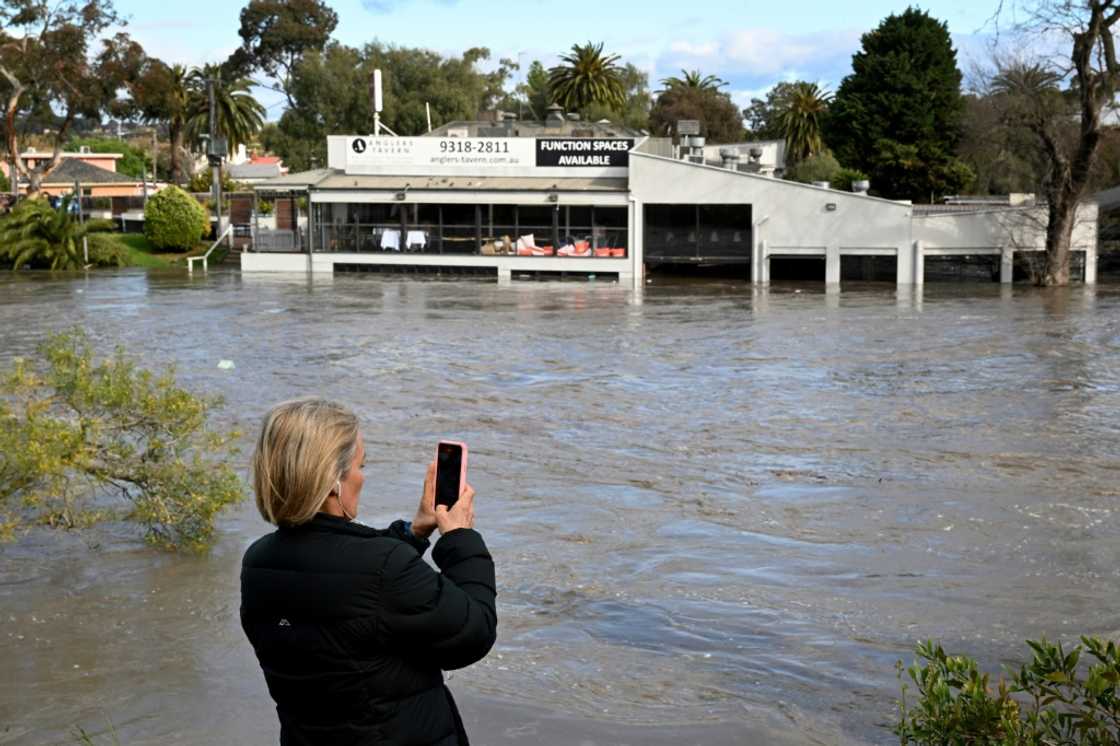 A woman films a flooded area in the Maribyrnong suburb of Melbourne on Friday A woman films a flooded area in the Maribyrnong suburb of Melbourne on Friday