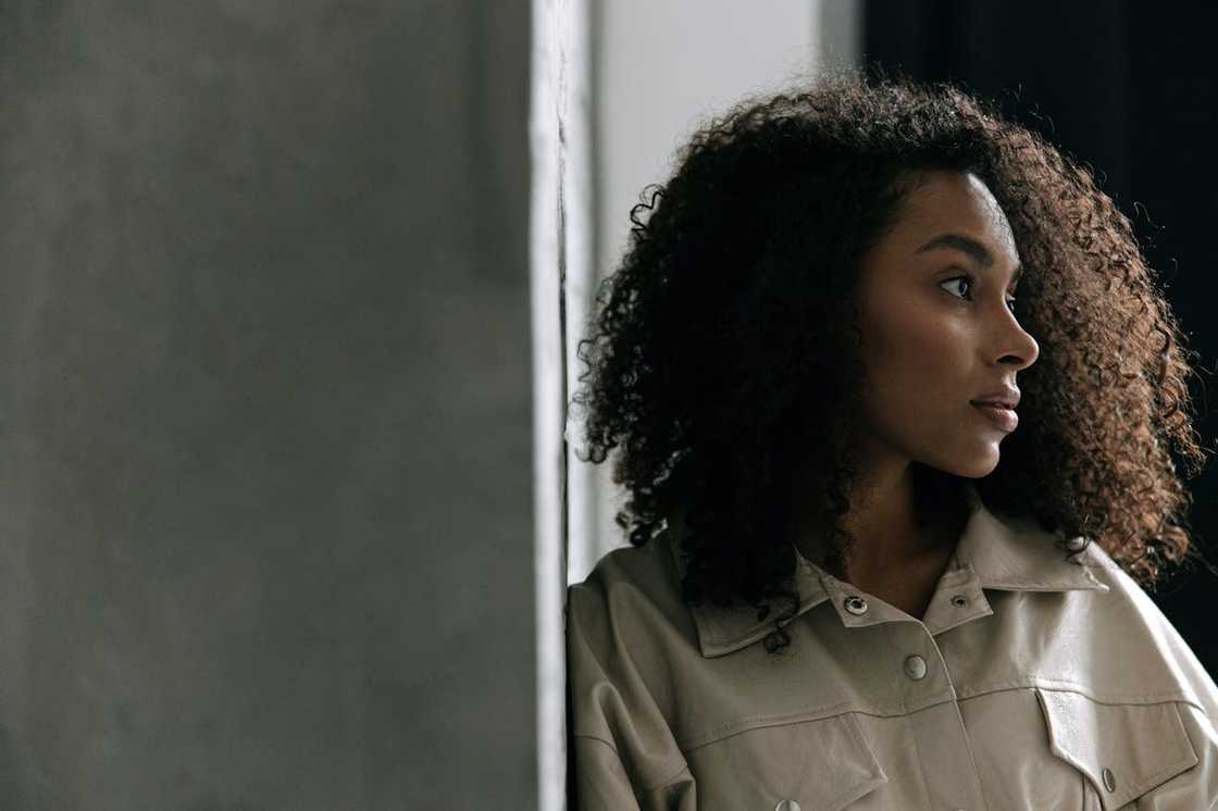 Woman standing by a wall, looking thoughtfully to the side. Woman standing by a wall, looking thoughtfully to the side.