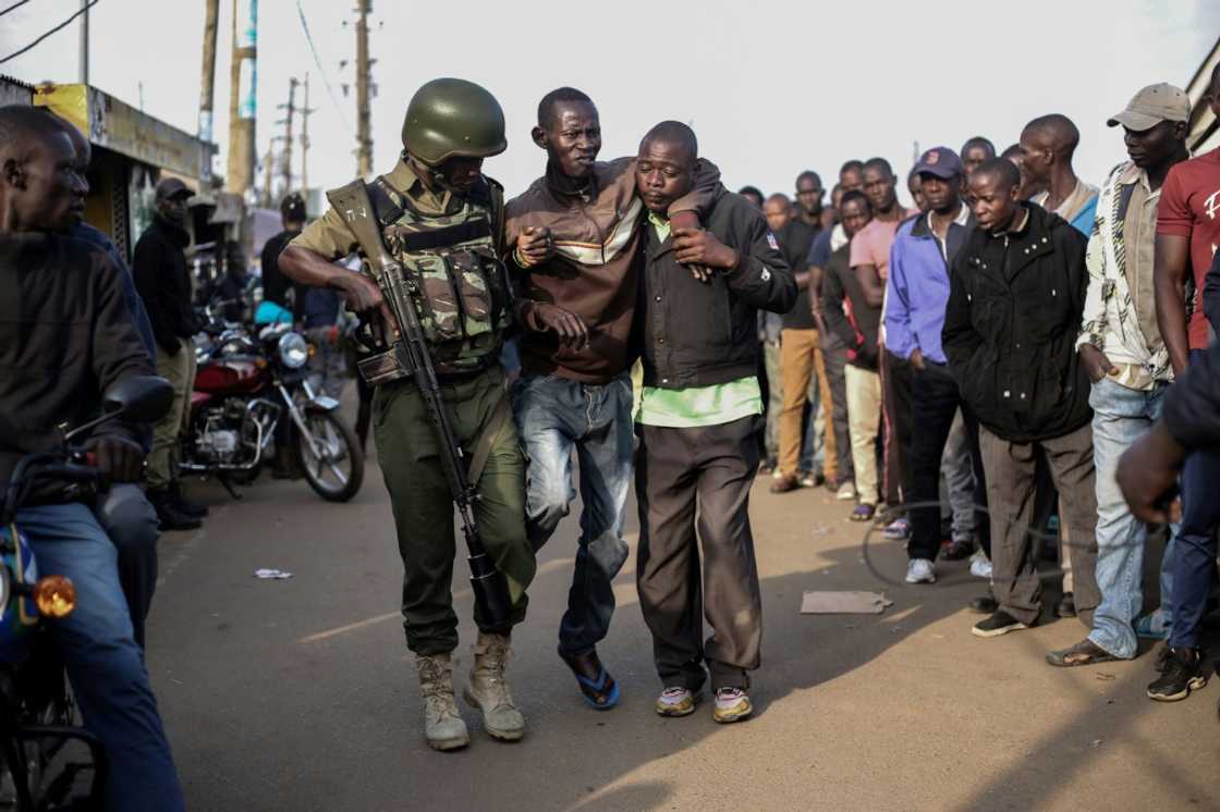 A Kenyan police officer helps disabled voter at a polling station in the lakeside city of Kisumu A Kenyan police officer helps disabled voter at a polling station in the lakeside city of Kisumu