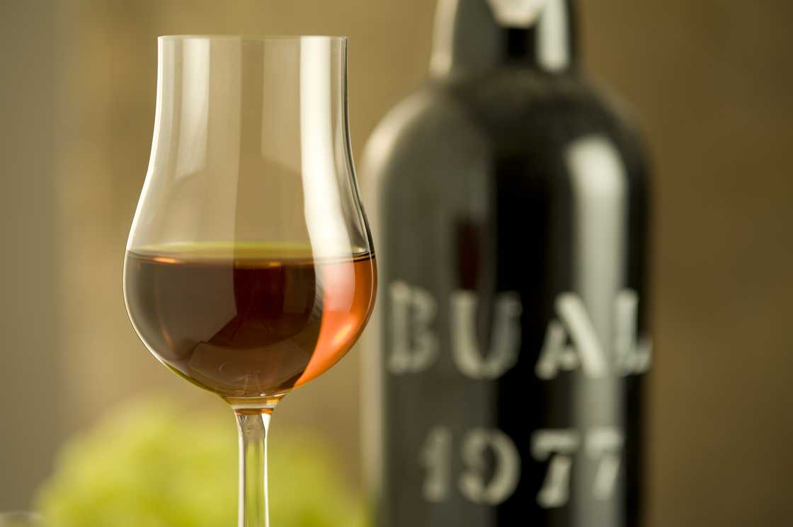 Madeira wine glass standing next to a bottle of wine.