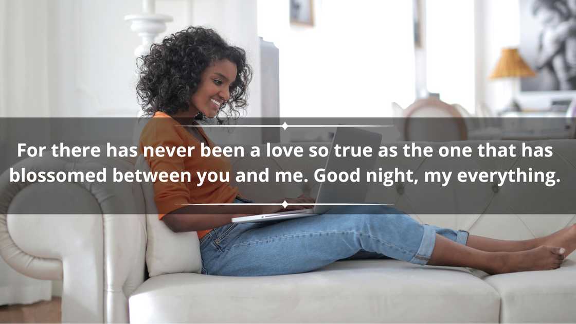 A smiling woman using a laptop on a cream couch